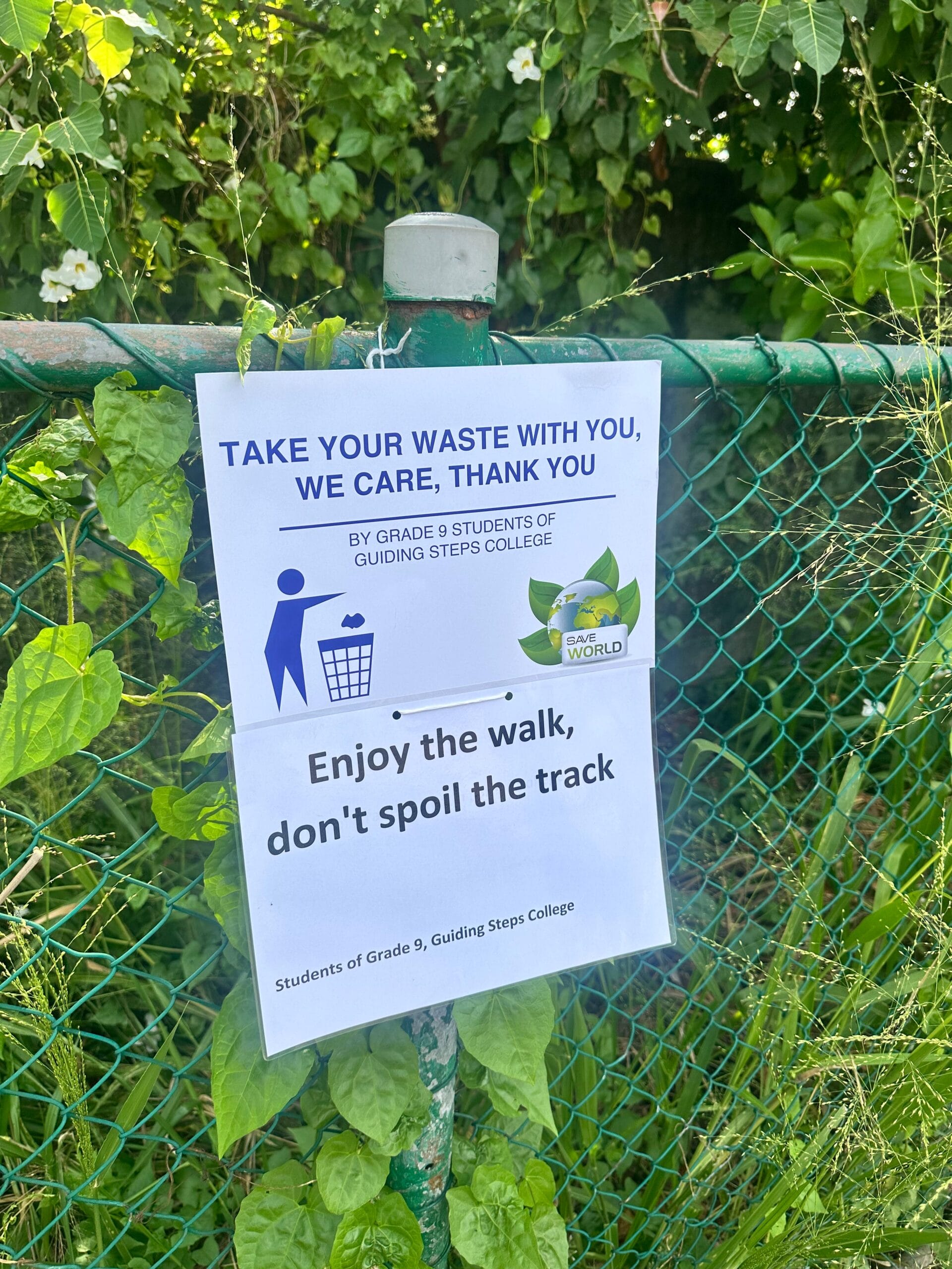 Anti-litter posters by Guiding Steps College students displayed on a fence along the walking track
