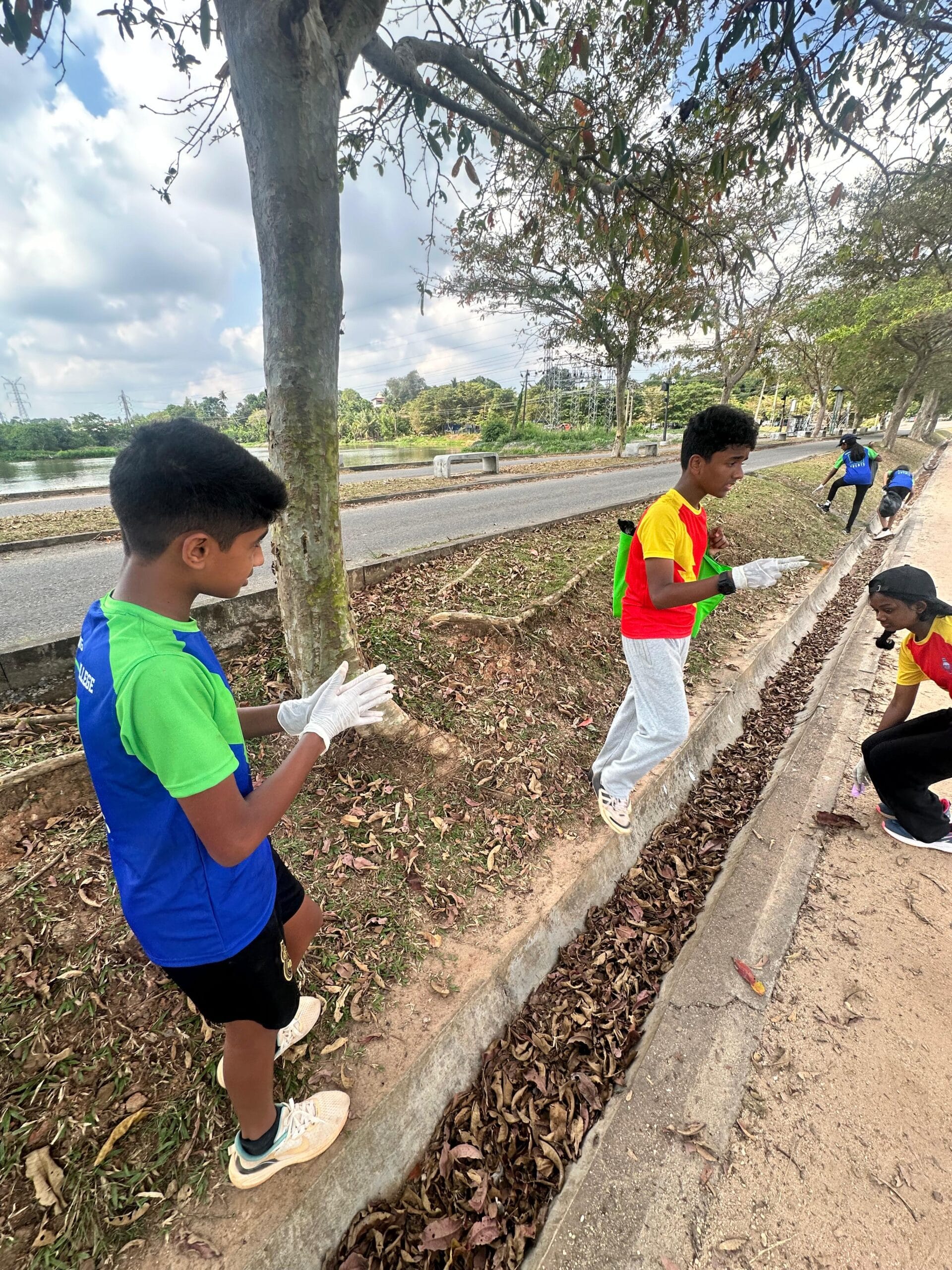 Students clearing litter from a roadside drain during the Guiding Steps College community clean-up