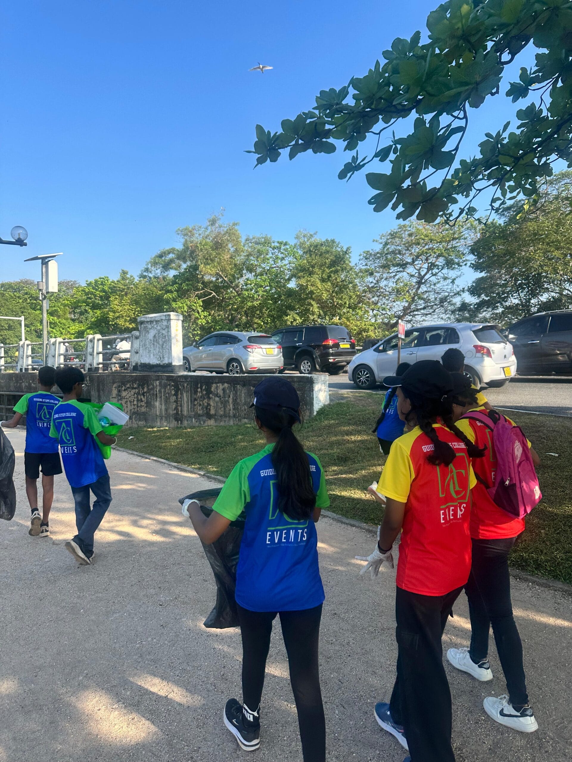 Guiding Steps College clean-up team walking the track with bin bags and collected waste
