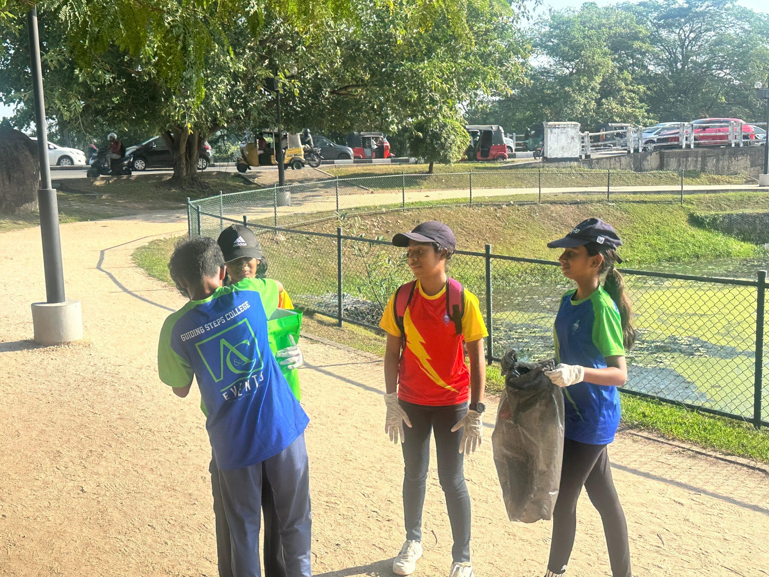 Gloved students holding a rubbish bag while cleaning the wetland park walking path