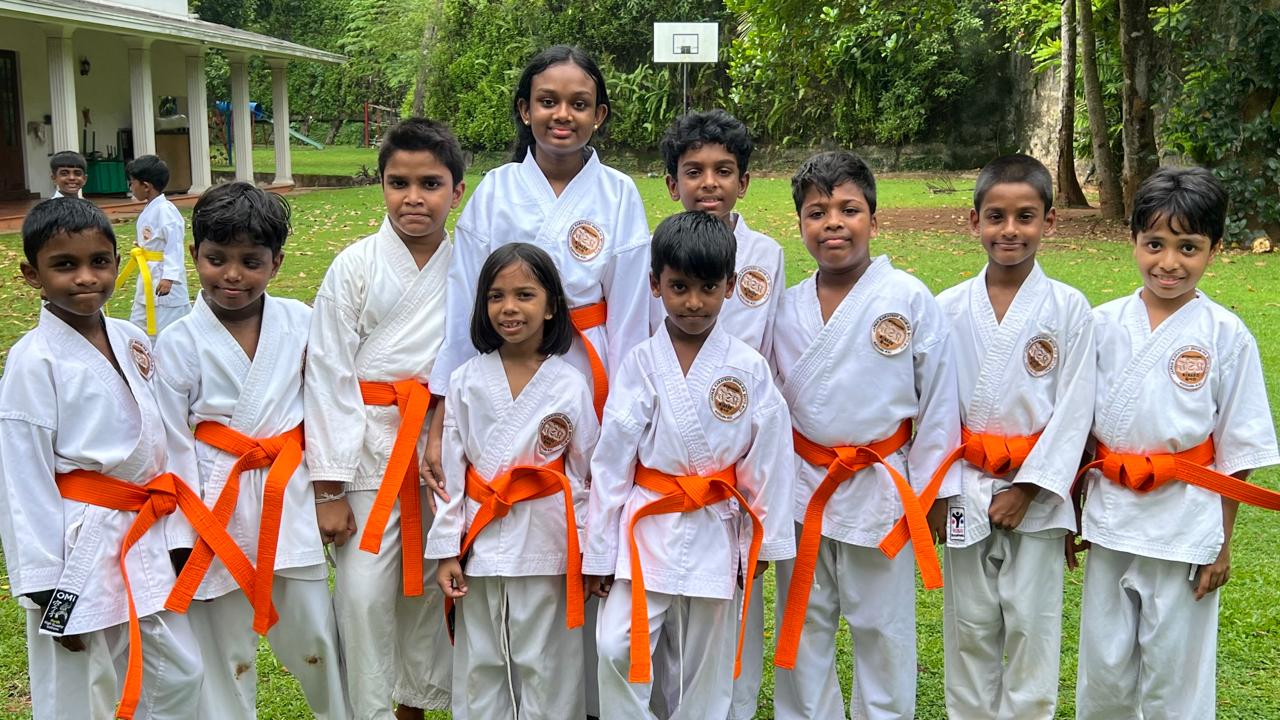 Orange belt karate students posing together on the lawn at Guiding Steps College