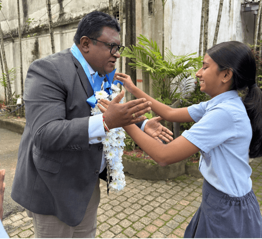A Guiding Steps College student welcomes H.E. Ambassador Wishwanath Aponso with a floral garland